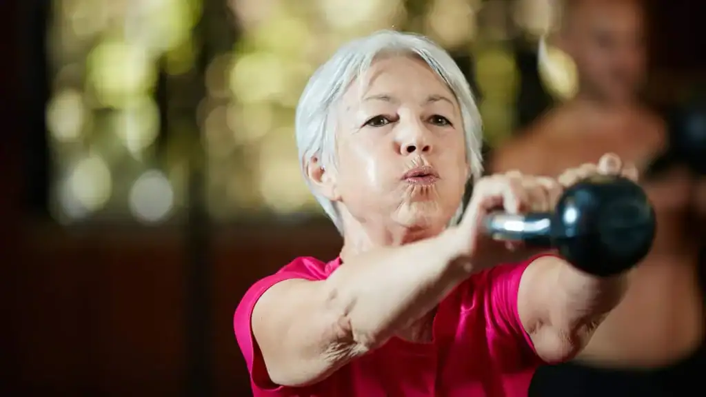Toning Arms After 60: Empowering Womens Fitness Through Effective Weight Training 1 Older woman doing weight training Sandwich to help her strength and longevity