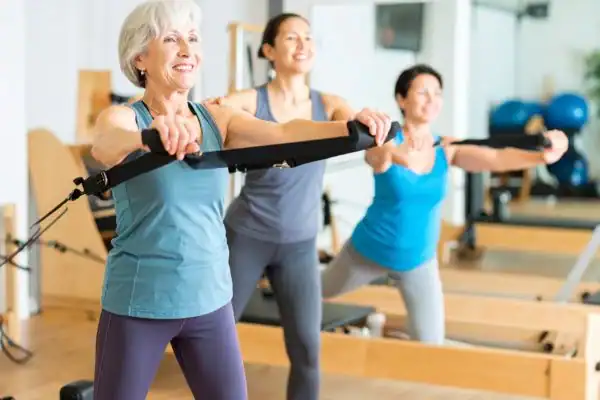 Toning Arms After 60: Empowering Womens Fitness Through Effective Weight Training 2 older woman doing weight training Sandwich and resistance in the gym to tone upper arms