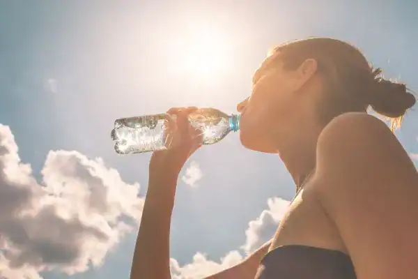 Hydration: The Secret Ingredient for a Toned Stomach and Enhanced Fitness 3 Image of woman drinking water to hydrate Sandwich after run.