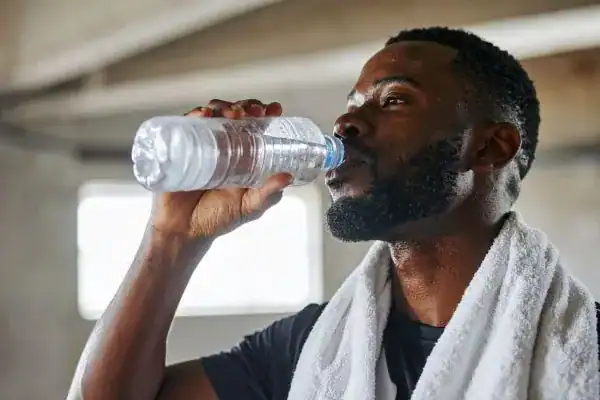Hydration: The Secret Ingredient for a Toned Stomach and Enhanced Fitness 1 Image of man drinking water to improve hydration Sandwich after work out.